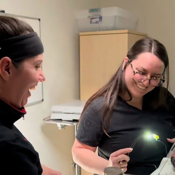 two female veterinary technicians smiling and collaborating on patient care